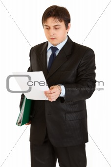 Serious modern businessman with folder in hand exploring document
