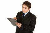 Serious young businessman making notes in document
