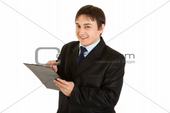 Smiling young businessman making notes in document
