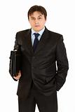 Serious young businessman with  briefcase in hand
