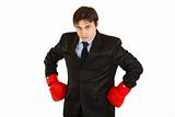 Angry young businessman with boxing gloves 
