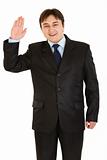 Friendly modern businessman showing salutation gesture
