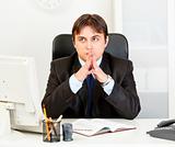 Pensive modern businessman sitting at desk in office
