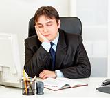 Bored modern businessman sitting at desk in  office
