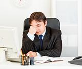 Tired modern businessman sitting at office desk
