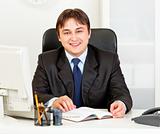 Smiling modern businessman sitting at office desk
