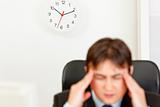 Stressed businessman  aware of approaching deadline. Focus on clock
