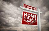 Red Foreclosure Home For Sale Real Estate Sign Over Ominous Cloudy Sky.