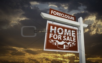 Red Foreclosure Home For Sale Real Estate Sign Over Beautiful Clouds and Sunset Sky.