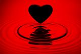 Black heart siluett over red water ripples
