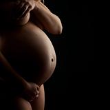 A naked pregnant woman on black background