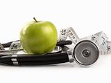 Green apple and measuring tape with stethoscope on white