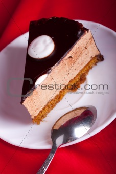 chocolate cake with spoon on red silk background