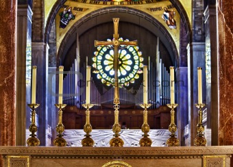 Ornate candlesticks on altar in church with gold cross