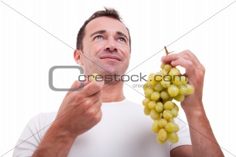 handsome man eating a green grapes, isolated on white background. Studio shot.