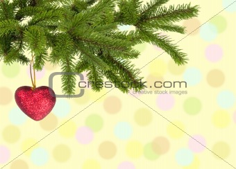 Christmas green branch with red heart over yellow background