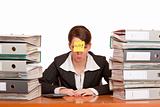 business woman in office between folder stacks needs help
