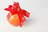 Orange tangerine with red goldish striped bow as a gift