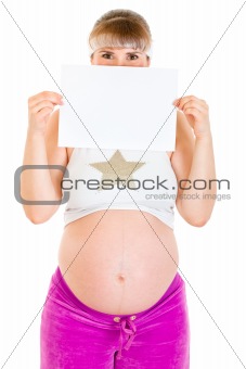 Pregnant woman holding empty white  paper in front of her face
