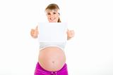 Smiling beautiful pregnant woman holding empty white  paper
