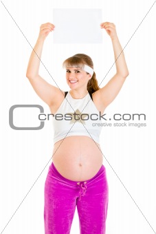Smiling beautiful pregnant woman holding empty white  paper over her head
