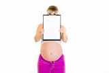 Pregnant woman holding blank clipboard in front of her face
