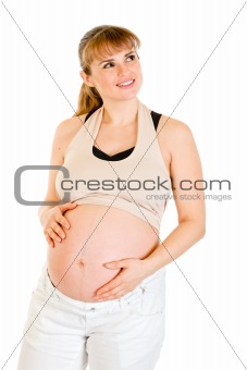 Dreaming beautiful pregnant woman touching her belly isolated on white

