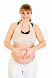Smiling pregnant woman making heart with her hands on tummy
