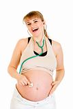 Laughing pregnant woman holding stethascope on her belly
