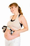 Happy pregnant woman holding headphones on her belly
