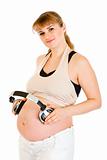 Smiling pregnant woman holding headphones on her tummy
