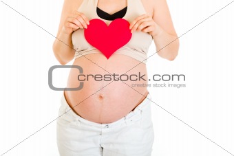 Pregnant woman holding paper heart in her hands. Close-up.
