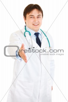 Smiling medical doctor stretches out hand for handshake
