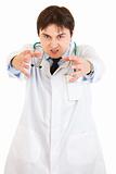 Angry medical doctor with stethoscope wants to catch you
