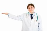 Smiling medical doctor presenting something on empty hand
