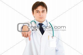 Serious young medical doctor pointing finger down
