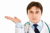 Serious  doctor presenting something on empty hand

