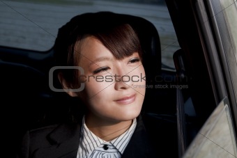 Beautiful business woman sitting in the car and looking out car window