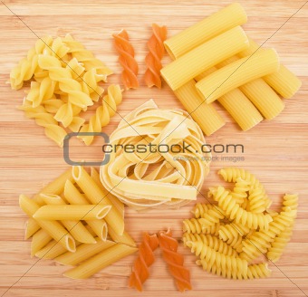 Different kinds of pasta on the wooden background 