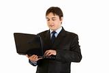 Smiling modern businessman working on laptop
