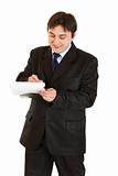 Smiling young businessman making notes in document
