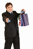 Smiling young businessman with shopping bags giving credit card
