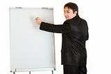 Smiling modern businessman giving presentation using flipchart, place for text
