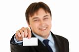 Smiling modern businessman holding blank business card
