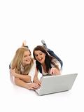 two Young pretty girl friends surfing in internet on laptop