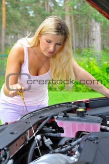 Young woman checking oil level in the car 