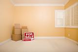 Moving Boxes, For Sale and Foreclosure Real Estate Signs on Floor in Empty Room with Copy Space on Blank Wall.