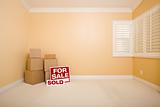 Moving Boxes, For Sale and Sold Real Estate Signs on Floor in Empty Room with Copy Space on Blank Wall.