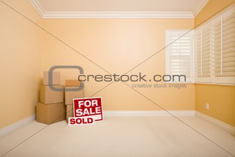 Moving Boxes, For Sale and Sold Real Estate Signs on Floor in Empty Room with Copy Space on Blank Wall.