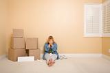 Upset Woman with Tissues on Floor Next to Boxes and Blank Sign in Empty Room.